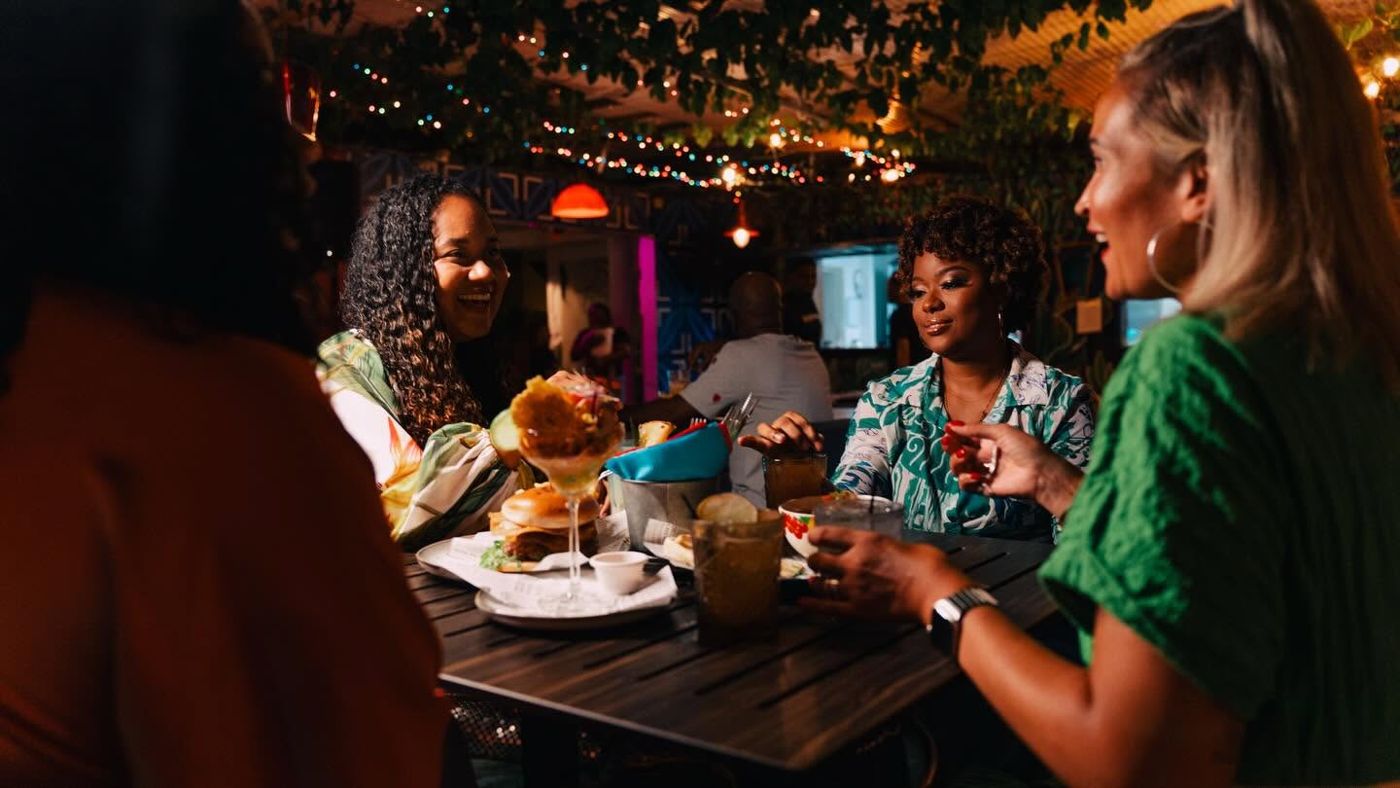 Friends laughing over burgers and drinks at Bario
